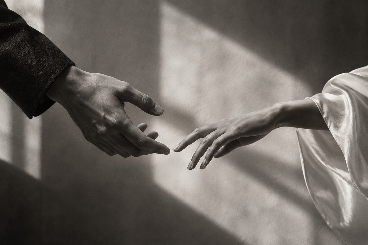 Original monochrome fashion artwork of two anonymous hands almost meeting across luminous space